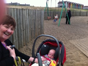 Picture of my mum, daughter, aunt & niece playing at South Beach Park with colourful beach huts in the background.